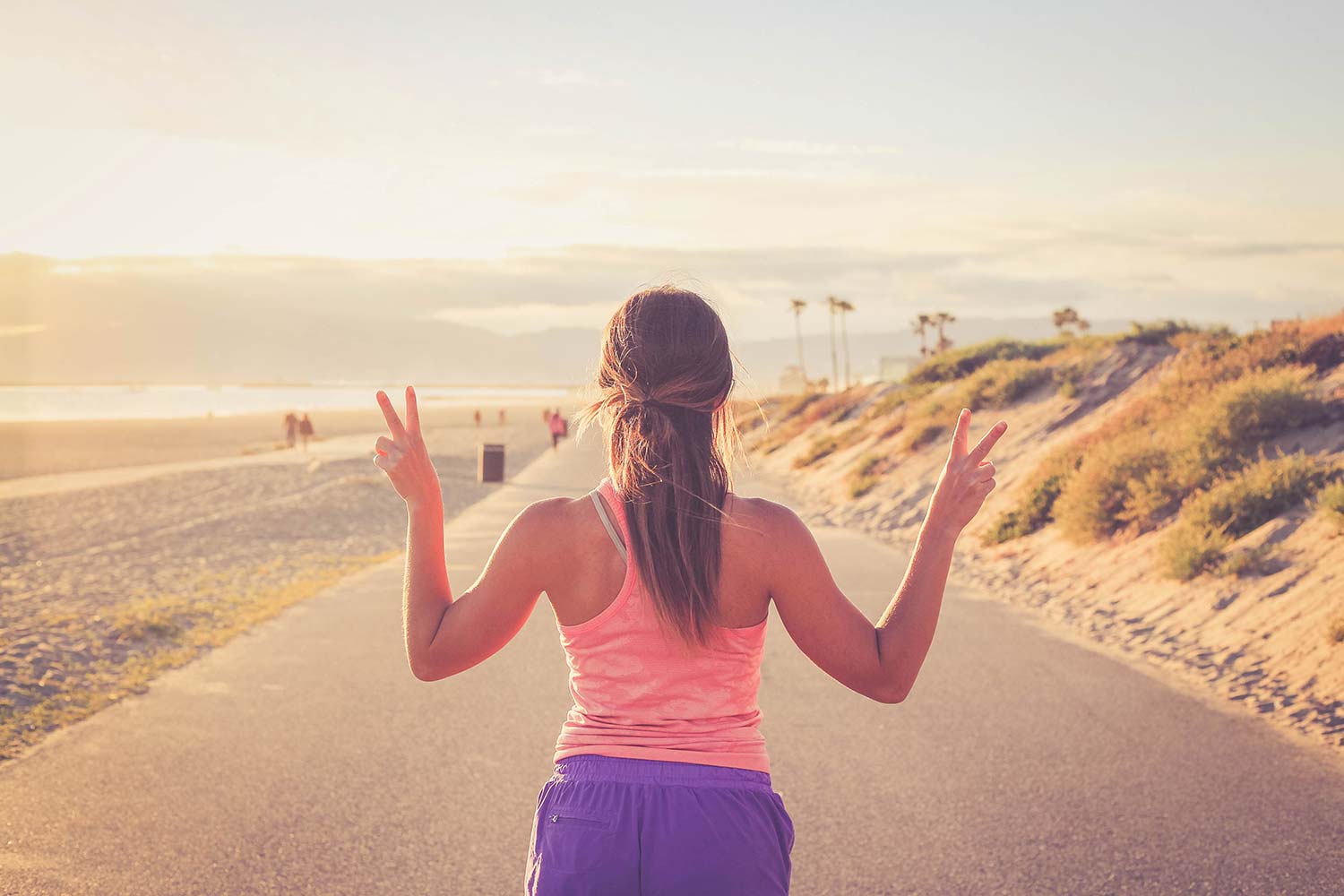Tan female running on a boardwalk near the beach.