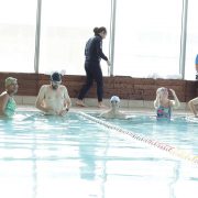 Friends swimming and laughing in a pool.