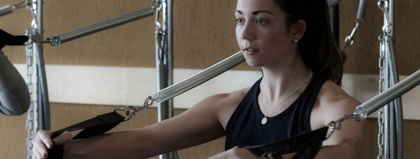 Woman working out using a Pilates apparatus.
