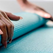Woman rolling up a yoga mat.