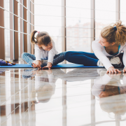 Woman and girl stretching together in yoga studio.