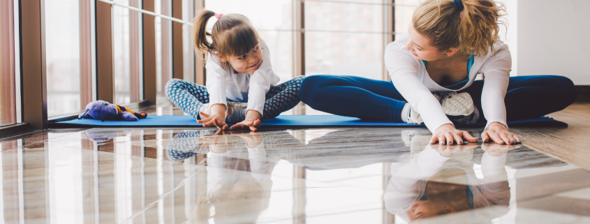 Woman and girl stretching together in yoga studio.