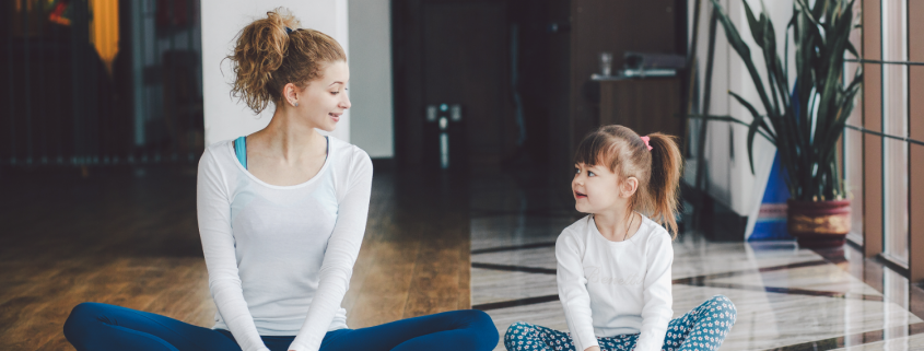 Woman and girl sitting together in yoga studio