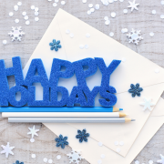 Happy Holidays graphic on a table with pencils and snowflakes