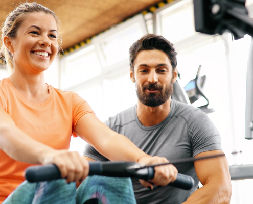 Image of a woman using a rowing machine with a personal trainer.
