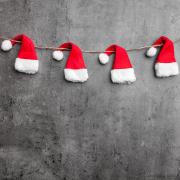 Santa hats on a string against gray wall