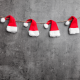Santa hats on a string against gray wall