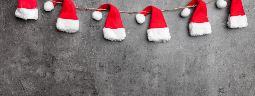 Santa hats on a string against gray wall