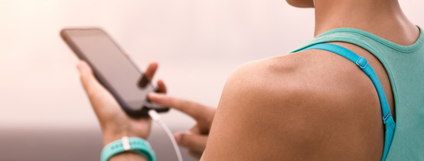 Female runner holding phone and listening to music with headphones on.