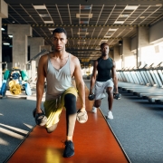Two male persons doing exercise with dumbbells, training in gym. Fit workout in sport club, healthy lifestyle, fitness