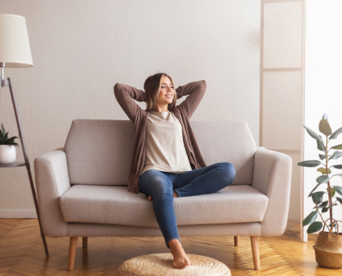 Millennial girl relaxing at home on couch, enjoying weekends, empty space