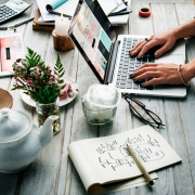 women at large table with computers, tea pot, journals