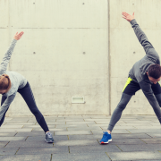 Man and woman outside in running gear stretching