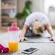 Woman stretching on the floor of her living room with weights and phone nearby.