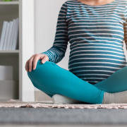 Pregnanct woman sitting cross legged on rug at home