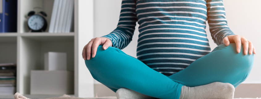 Pregnanct woman sitting cross legged on rug at home