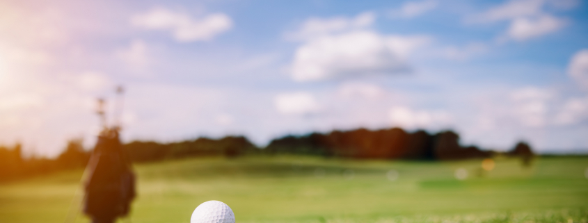 White golf ball on a green grass. Golf course. Summer luxury activities.