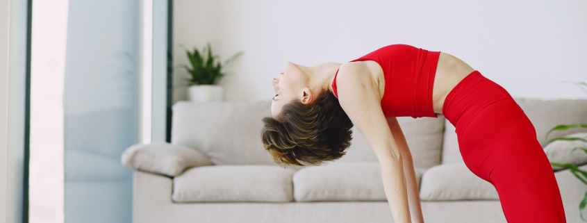 Woman in camel pose doing yoga on mat in home.
