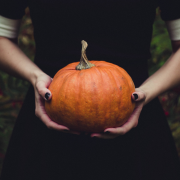 Girl wearing black dress holding a pumpkin