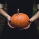 Girl wearing black dress holding a pumpkin