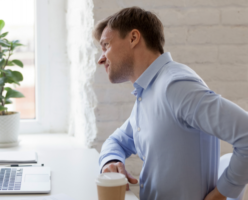 Man at desk holding his lower back