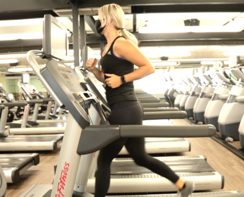 Woman running on treadmill wearing a mask