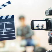 Photo of clapboard and digital camera in front of two people sitting