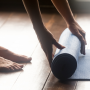 Woman unrolling yoga mat on floor