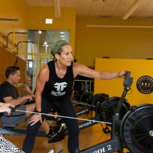 Woman instructing participant on rower in a G.row group fitness class in Chicago
