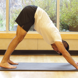Man in downward facing dog in a Yoga For Athletes group fitness class in Chicago
