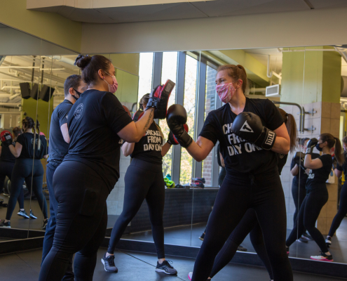 Two women participating in a small group boxing class at a gym