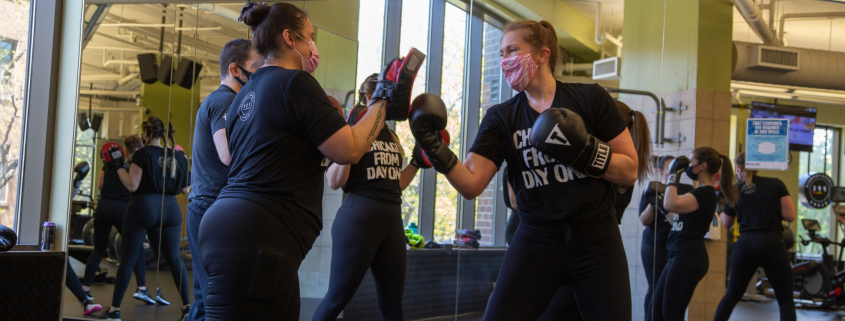 Two women participating in a small group boxing class at a gym