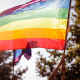 Person holding up a rainbow Pride flag outside