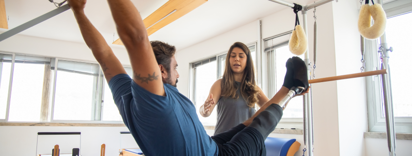 Woman instructing a man on the Pilates apparatus