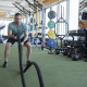 Man using battle ropes on turf inside a gym
