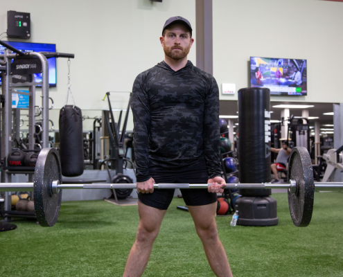 Man in gym holding barbell with weights on it.