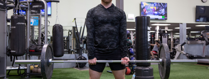 Man in gym holding barbell with weights on it.
