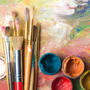 Paint brushes and different colors of paint on a canvas