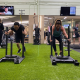 Two people on a turf pushing weighted sleds during a Faction workout class.