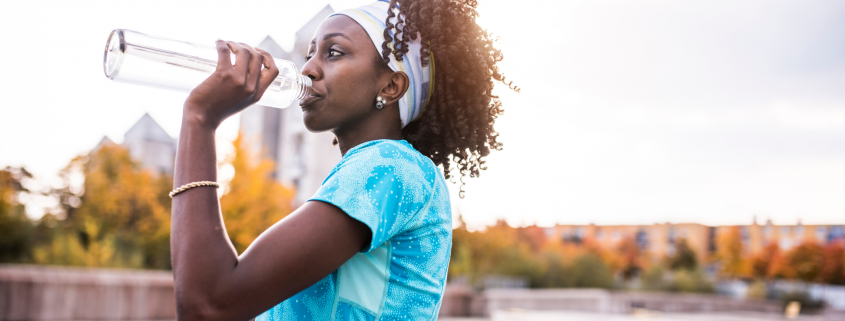 Woman drinking water out of a water bottle outside