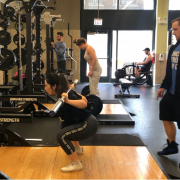 A woman at a squat rack with her trainer