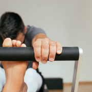 Man stretching his hamstrings on a Pilates reformer
