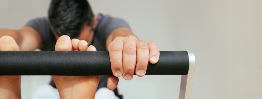 Man stretching his hamstrings on a Pilates reformer
