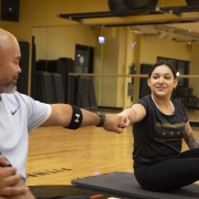 2 people bumping fists while sitting on exercise mats