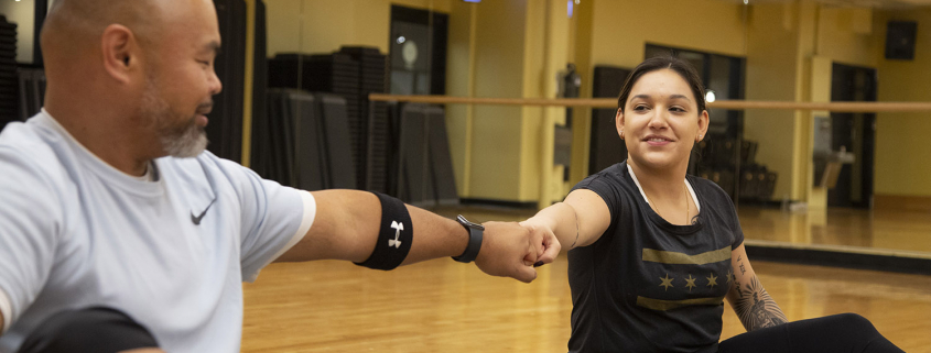 2 people bumping fists while sitting on exercise mats