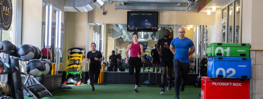 Image of 4 people running on indoor turf in a gym