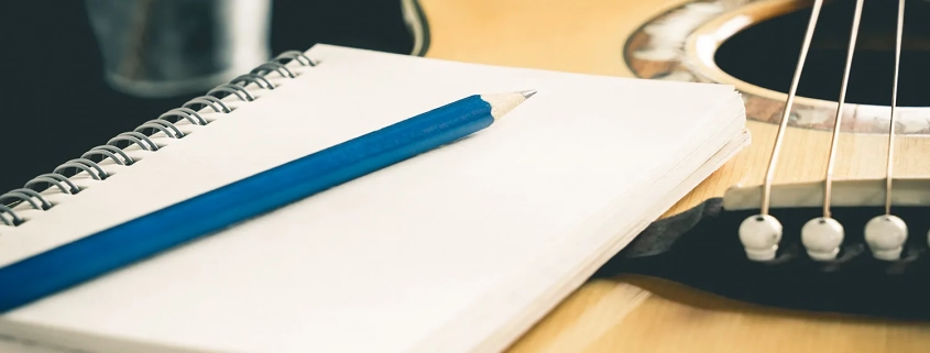 Guitar with a pen and notepad next on it