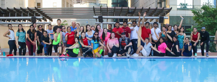 Group fitness dance class on outdoor pool deck.