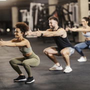 Sporty friends doing squat endurance in a gym together.