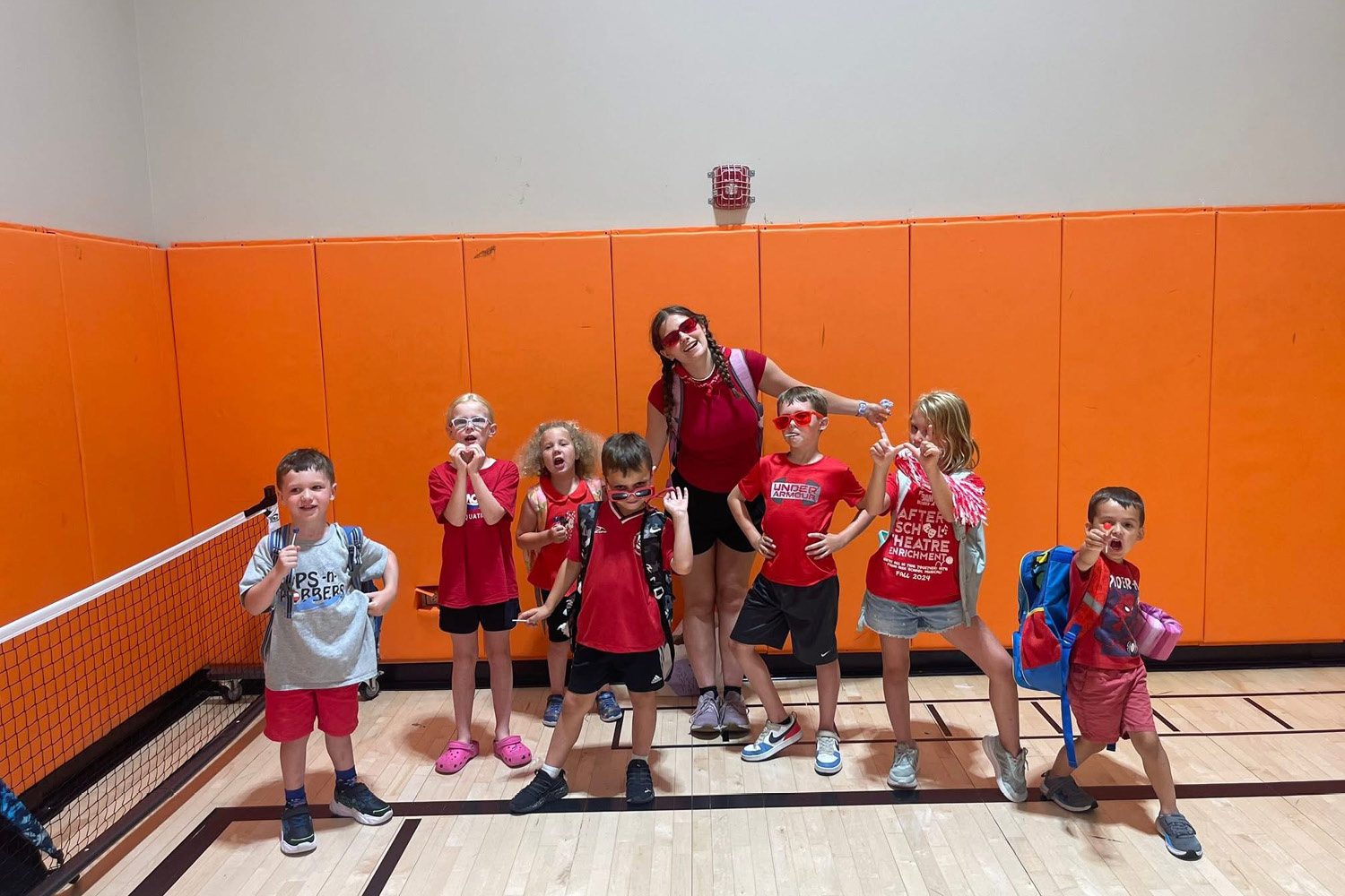Kids posing with kids club employee dressed in red attire